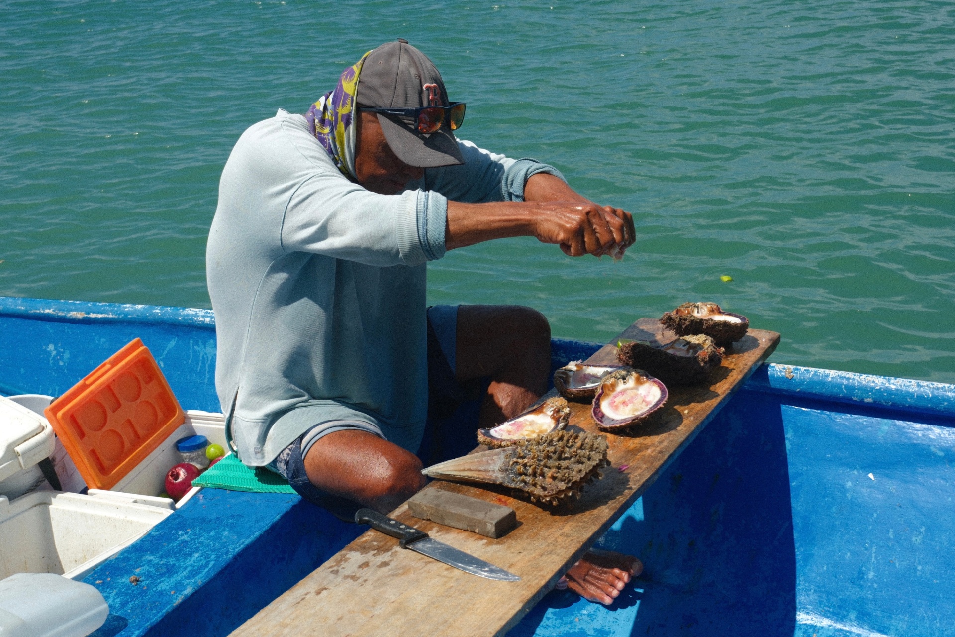 Fisherman preparing fresh shellfish on a blue boat at sea
