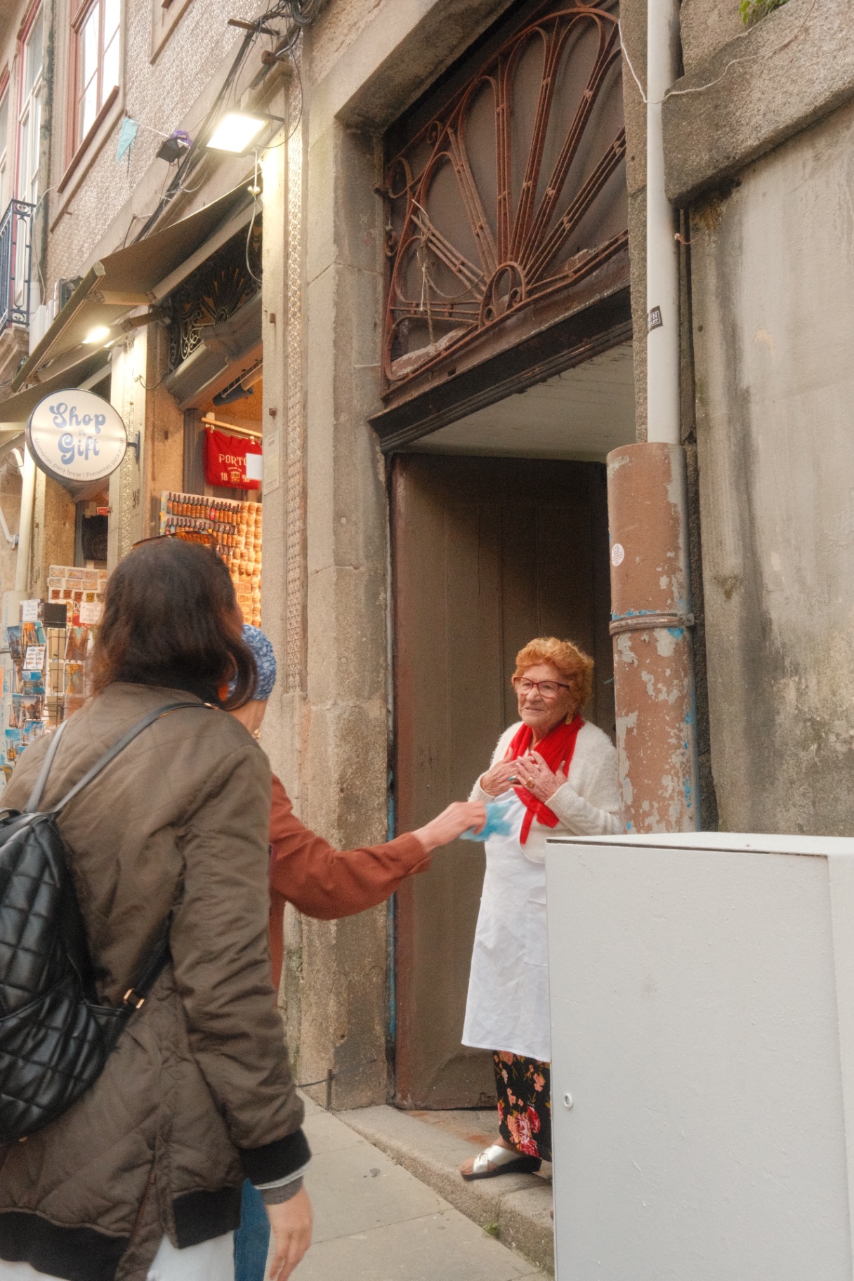 Woman greeting a shopkeeper in a Porto alley